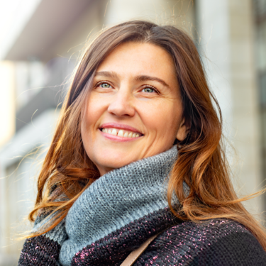 Eine Frau mit langen braunen Haaren lächelt.