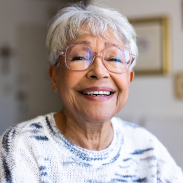 Eine Frau mit kurzen grauen Haaren und einer Brille lacht.